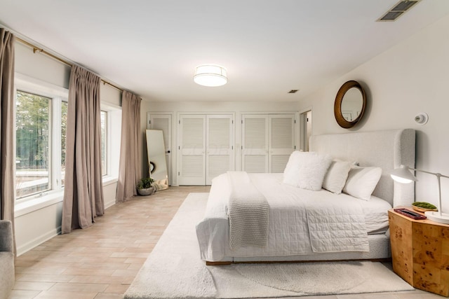 bedroom with light wood-type flooring and two closets