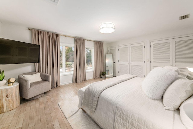 bedroom with multiple closets and light hardwood / wood-style flooring