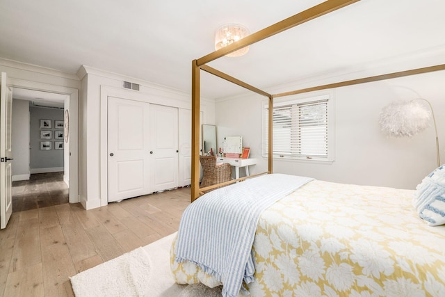 bedroom with crown molding, light hardwood / wood-style floors, and a closet