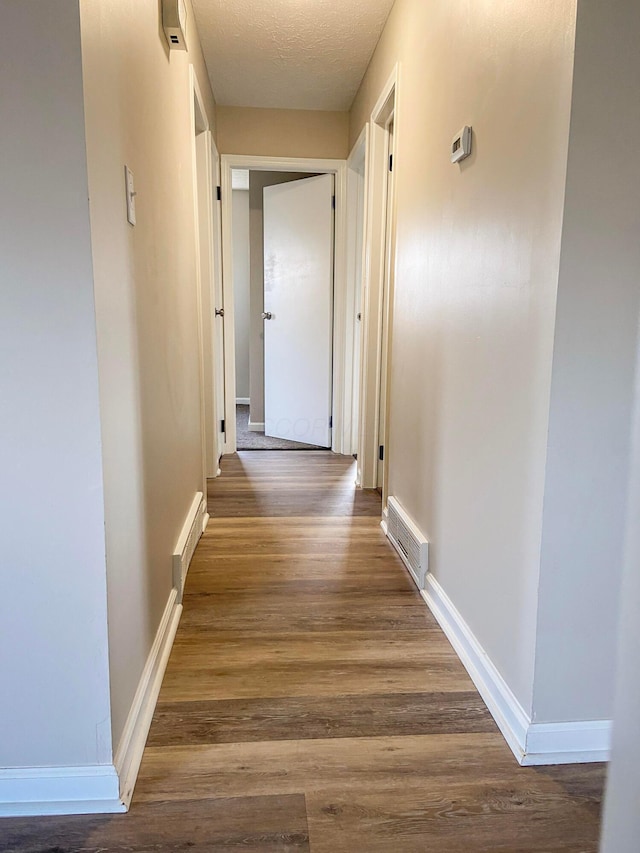 hall with dark wood-type flooring and a textured ceiling