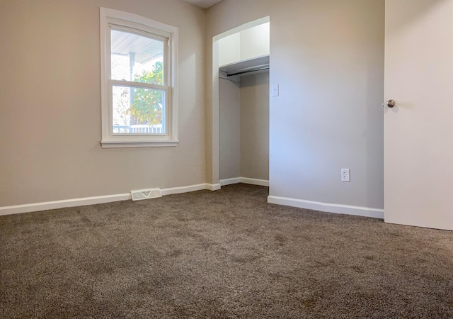 unfurnished bedroom featuring dark colored carpet and a closet