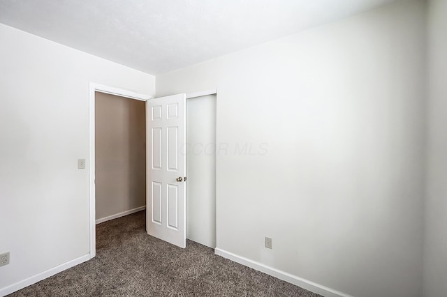 unfurnished bedroom with dark carpet