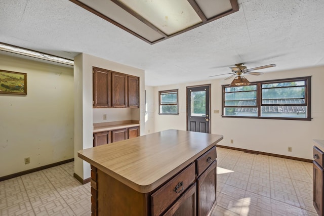 kitchen with plenty of natural light, a center island, a textured ceiling, and ceiling fan