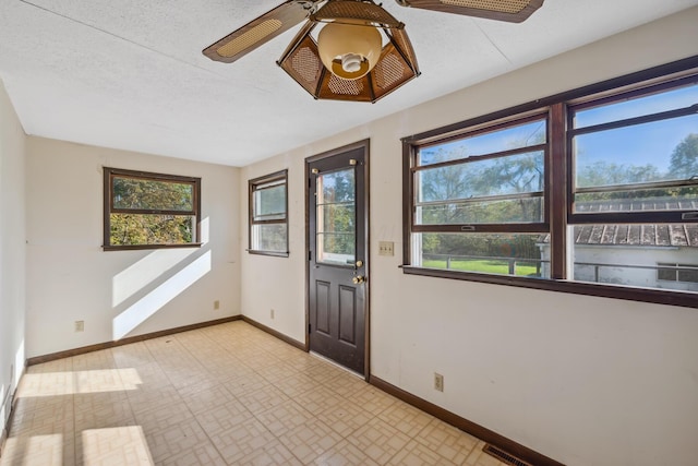 foyer entrance featuring a textured ceiling, ceiling fan, and a healthy amount of sunlight