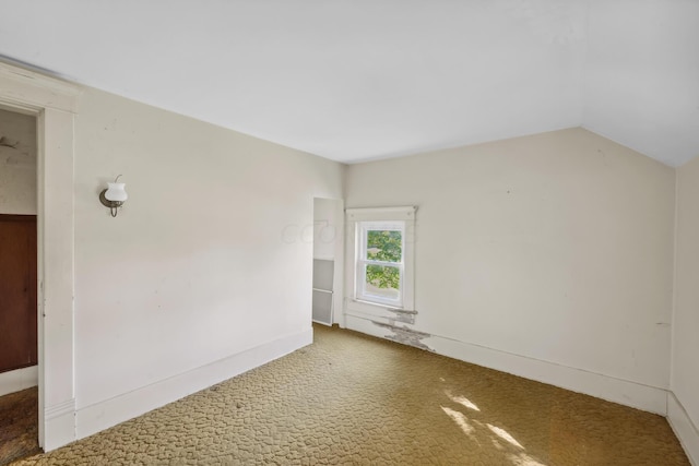 carpeted empty room with vaulted ceiling