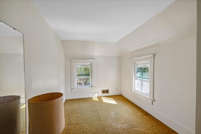 carpeted empty room featuring vaulted ceiling