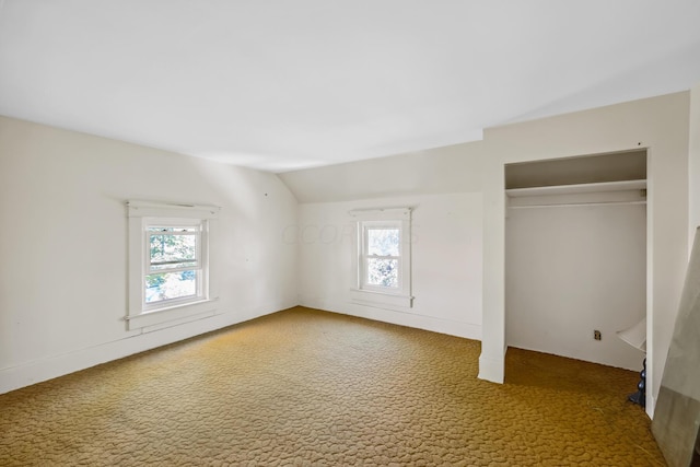 unfurnished bedroom featuring multiple windows, a closet, carpet floors, and vaulted ceiling