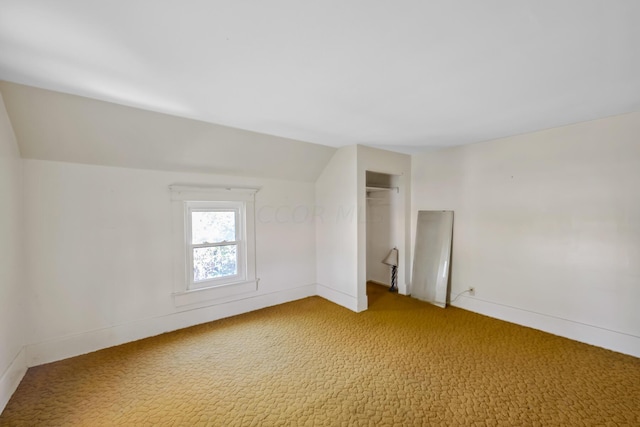 interior space featuring carpet floors, vaulted ceiling, and a closet