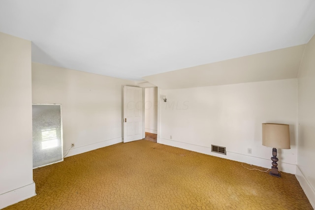 carpeted empty room with vaulted ceiling