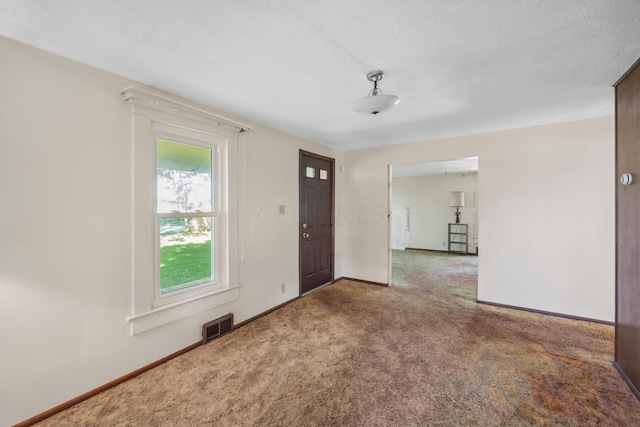 carpeted foyer featuring a textured ceiling