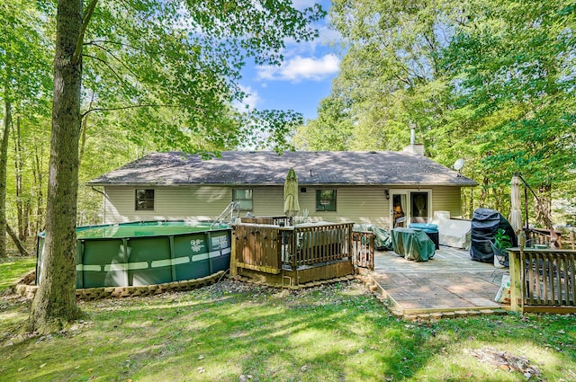 back of property with a swimming pool side deck, a yard, and a patio