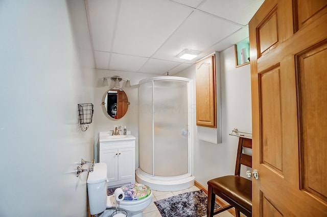 bathroom with toilet, a drop ceiling, a shower with shower door, and tile patterned flooring