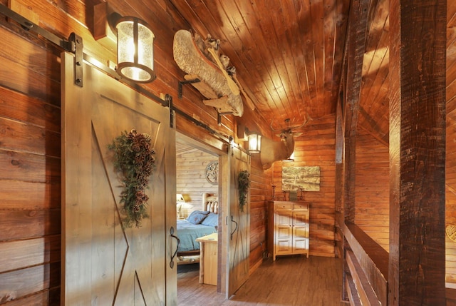 corridor with hardwood / wood-style floors, a barn door, wooden walls, and wood ceiling