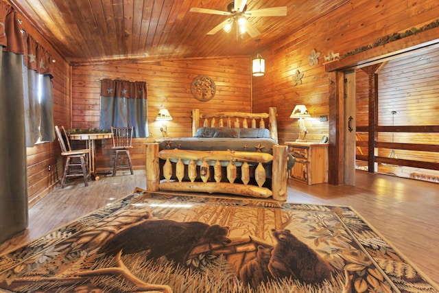 bedroom with wooden walls, hardwood / wood-style floors, wood ceiling, and vaulted ceiling