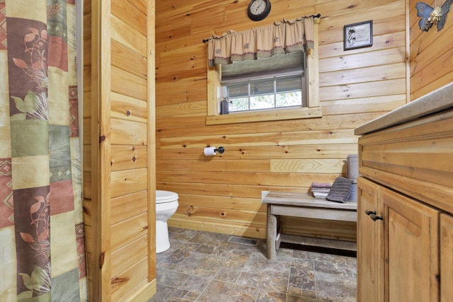 bathroom featuring wood walls and toilet