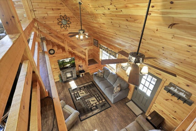 living room featuring dark hardwood / wood-style floors, high vaulted ceiling, ceiling fan, and wood walls