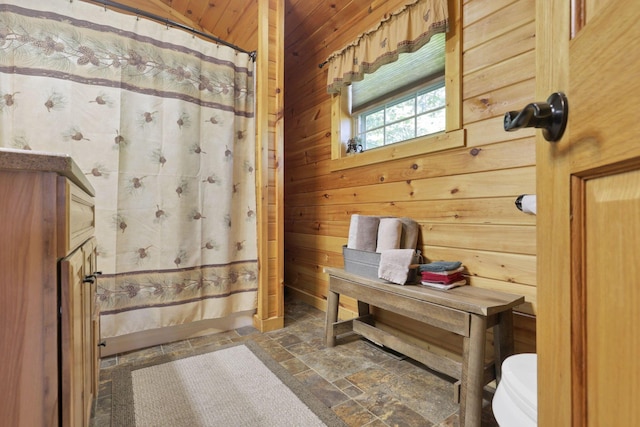 bathroom with curtained shower, wooden ceiling, and wooden walls