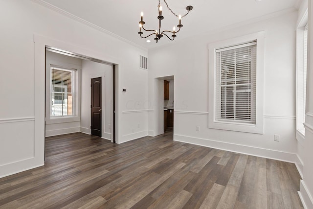 empty room featuring ornamental molding, dark hardwood / wood-style floors, and a notable chandelier