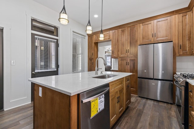 kitchen with appliances with stainless steel finishes, pendant lighting, a kitchen island with sink, and dark wood-type flooring