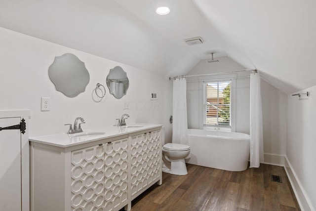 bathroom with wood-type flooring, vaulted ceiling, toilet, a bathtub, and vanity