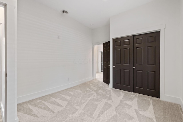 unfurnished bedroom with light carpet and a closet