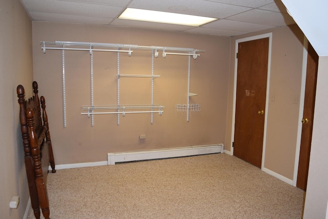 carpeted spare room featuring a drop ceiling and a baseboard heating unit