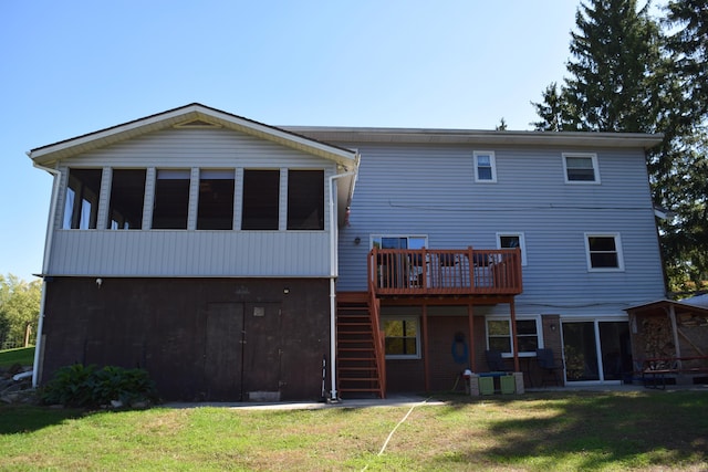 back of property featuring a sunroom, a deck, and a lawn