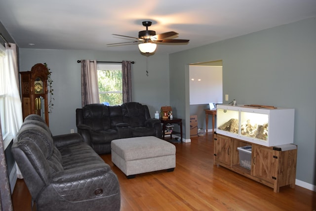 living room with ceiling fan, light wood-type flooring, and baseboard heating