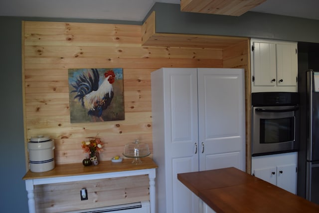 kitchen featuring white cabinets, baseboard heating, and stainless steel oven