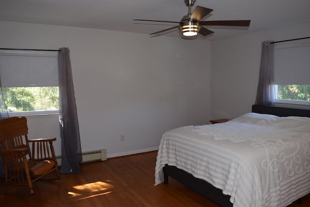 bedroom with ceiling fan, dark hardwood / wood-style floors, a baseboard heating unit, and multiple windows