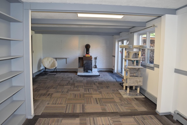 interior space with beamed ceiling, dark carpet, and a baseboard heating unit