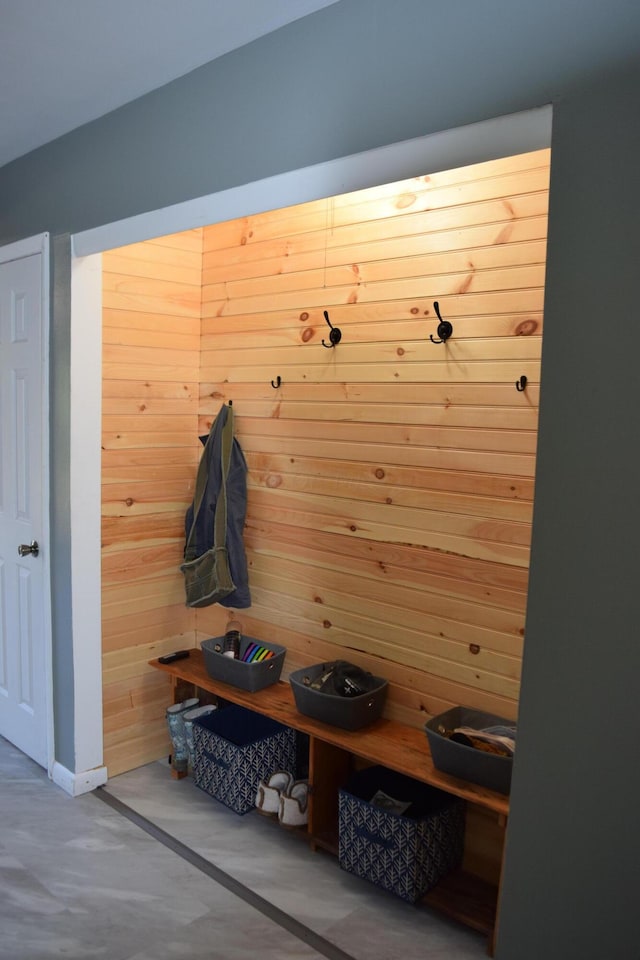 mudroom with concrete flooring and wooden walls