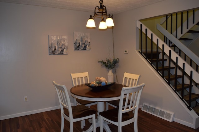 dining area featuring a textured ceiling, dark hardwood / wood-style flooring, and a notable chandelier