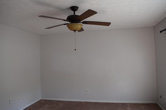 empty room featuring a textured ceiling, dark colored carpet, and ceiling fan