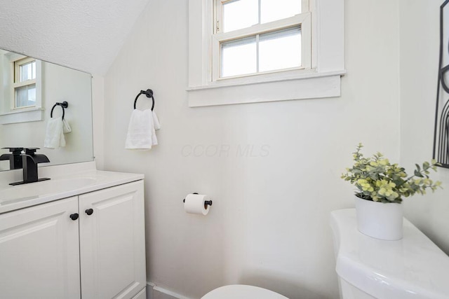 bathroom with a textured ceiling, vanity, and toilet