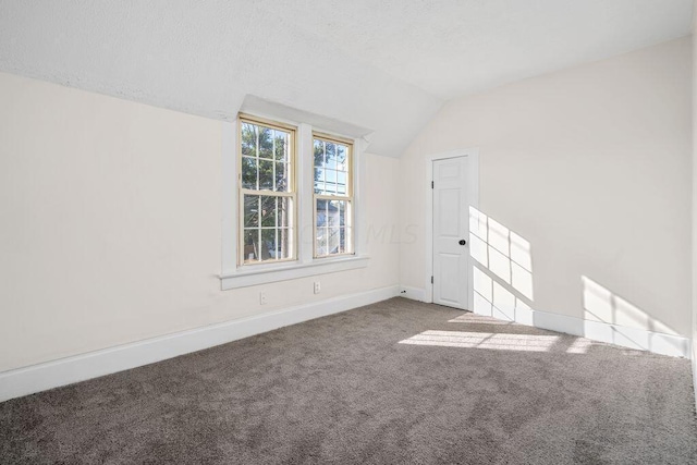 carpeted spare room with vaulted ceiling