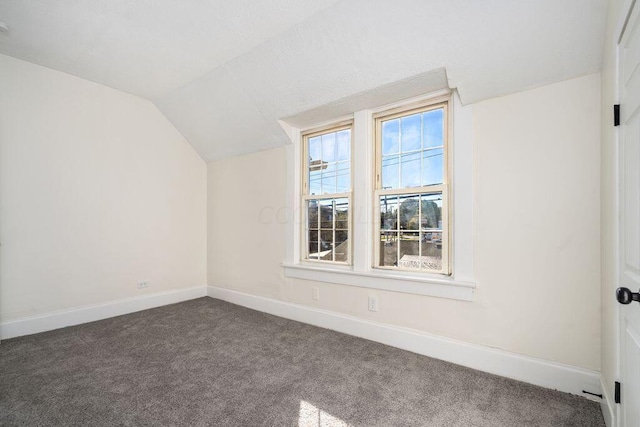 bonus room featuring vaulted ceiling and dark colored carpet