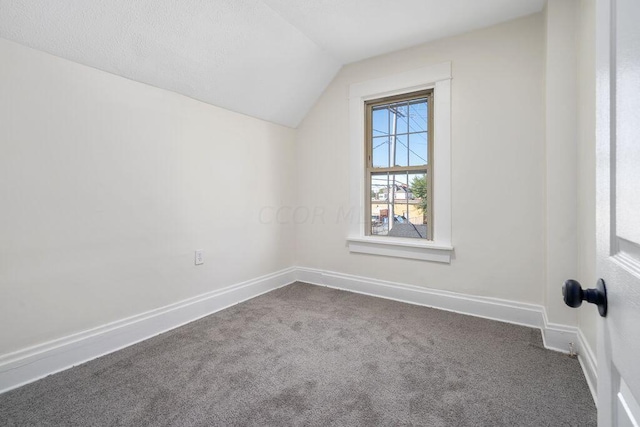 bonus room with vaulted ceiling and dark colored carpet