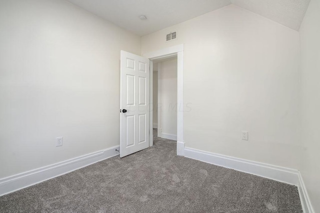 carpeted empty room featuring vaulted ceiling