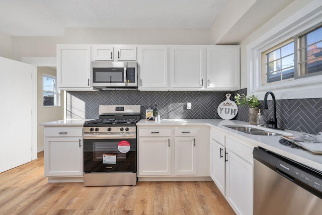 kitchen featuring white cabinets, appliances with stainless steel finishes, light hardwood / wood-style flooring, and sink