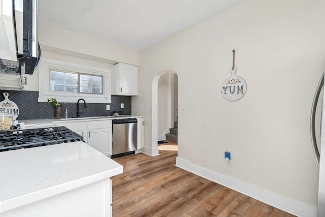 kitchen featuring decorative backsplash, stainless steel appliances, sink, white cabinets, and light hardwood / wood-style floors