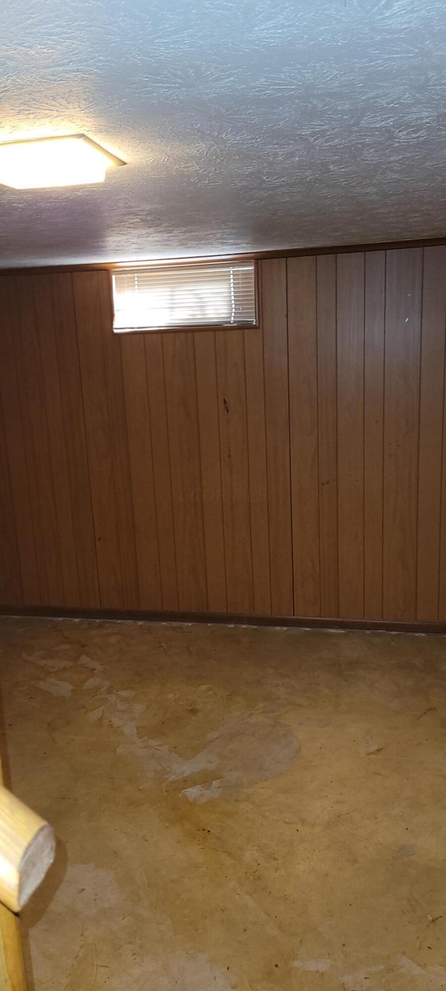 basement featuring a textured ceiling and wooden walls