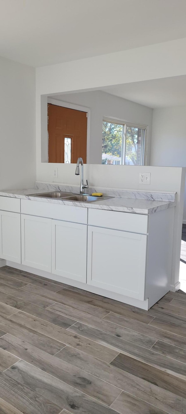 kitchen featuring hardwood / wood-style floors, white cabinets, and sink