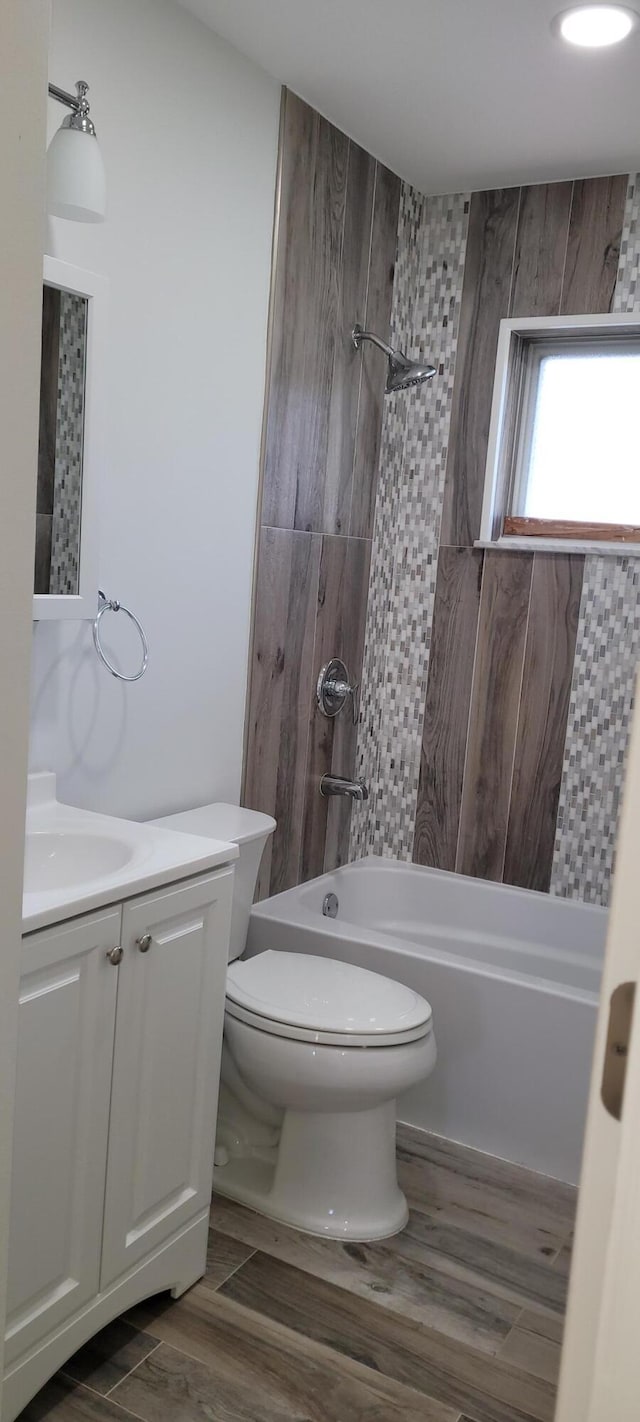 full bathroom featuring hardwood / wood-style floors, vanity, toilet, and tiled shower / bath