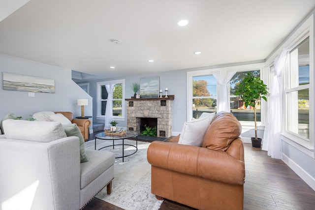 living room with a stone fireplace and dark wood-type flooring