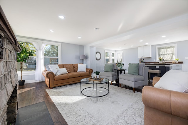 living room with a stone fireplace and hardwood / wood-style floors