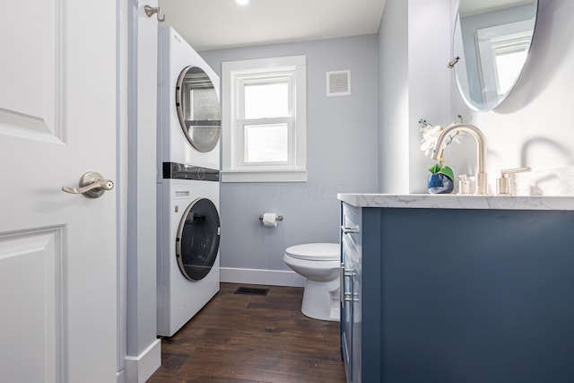 bathroom with hardwood / wood-style floors, vanity, toilet, and stacked washer / drying machine