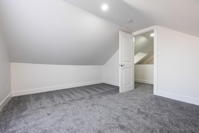 additional living space with dark carpet and lofted ceiling