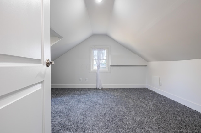 bonus room with dark carpet and lofted ceiling