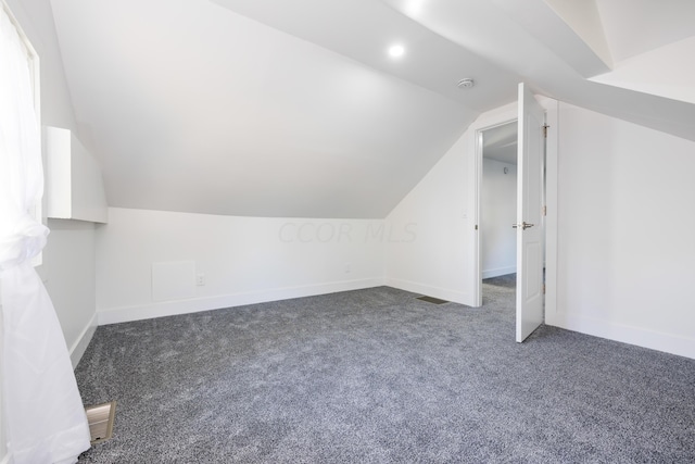 bonus room featuring dark colored carpet and vaulted ceiling